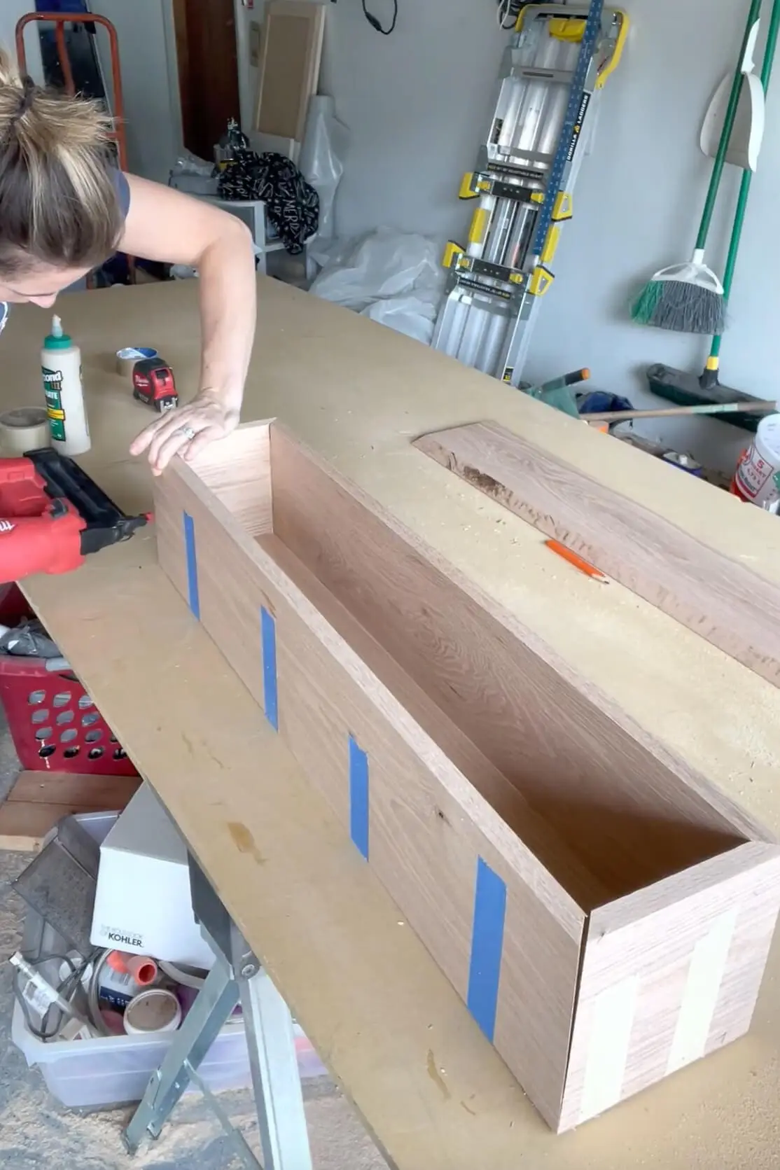 Securing the corners of a DIY fireplace mantel using a brad nailer for a sturdy assembly.